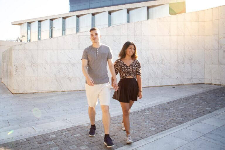 a couple is posing in front of the Acropolis Museum in Athens, Greece