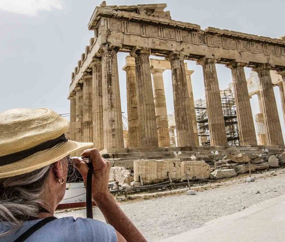 Female photographer taking a photo of the Parthenon columns at the Acropolis.